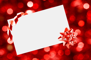 Christmas sheet of paper with bow on red defocused background