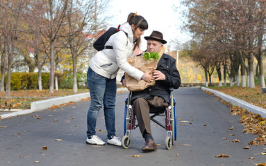 Man in a wheelchair being helped with groceries