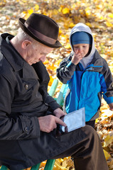 Grandfather using a tablet watched by his grandson