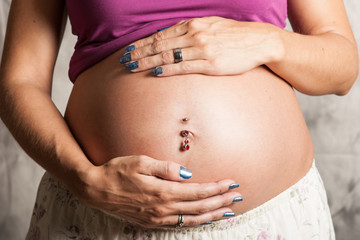 Woman with pierced navel holding her baby tummy