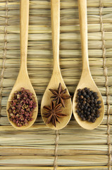 Three spices in a wooden spoons on wooden board