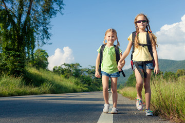 two girls with backpacks walking on the road