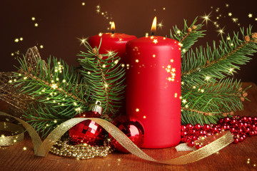 Two candles and christmas decorations, on brown background