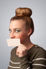 Cute girl holding white card at front of her lips with copy spac