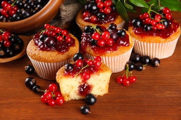 Tasty muffins with berries on wooden table