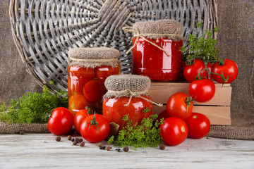 Tasty canned and fresh tomatoes on wooden table