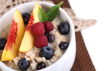 Oatmeal in cup with berries on napkins isolated on white