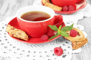 Cups of tea with cookies and raspberries on table close-up