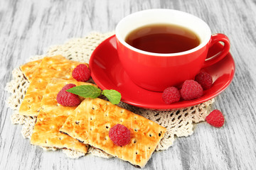 Cup of tea with cookies and raspberries on table close-up