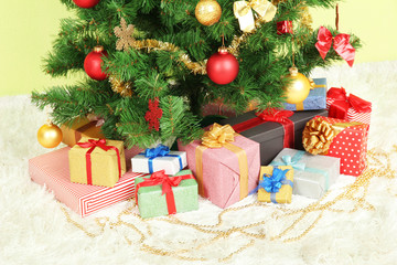 Decorated Christmas tree with gifts on green wall background