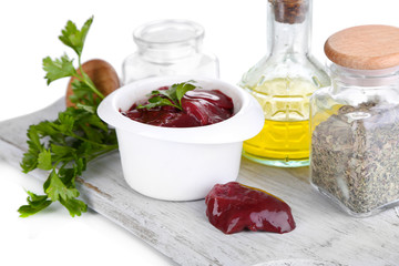 Raw liver in bowl with spices and condiments isolated on white