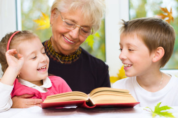 great-grandmother reading a book for grandchildren