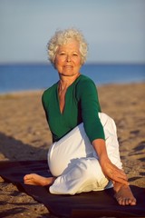 Fototapeta na wymiar Senior woman enjoying yoga on the beach