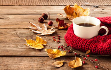Hot coffee and autumn leaves on vintage wood background