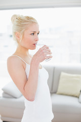 Side view of fit young woman drinking water at the gym