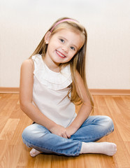 Smiling cute little girl sitting on floor