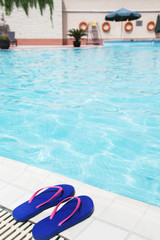 Fototapeta na wymiar Pair of blue flip flops by the pool side