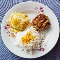Plate with burgers cooked poultry with rice and coleslaw.