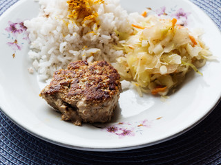 Plate with burgers cooked poultry with rice and coleslaw.