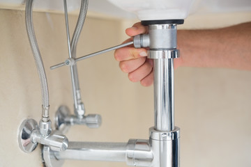 Extreme Close up of a plumber's hand and washbasin drain