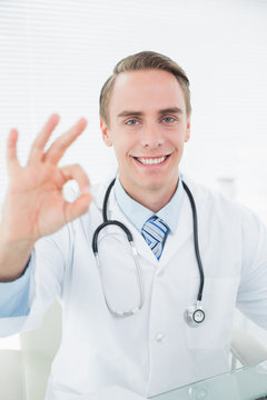 Smiling doctor gesturing okay sign at medical office