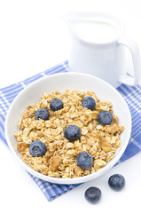 muesli with blueberries and jug of milk isolated on white