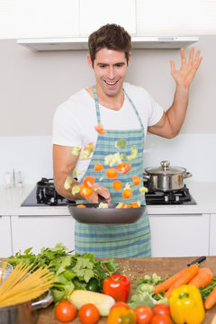 Cheerful Man Tossing Vegetables In Kitchen