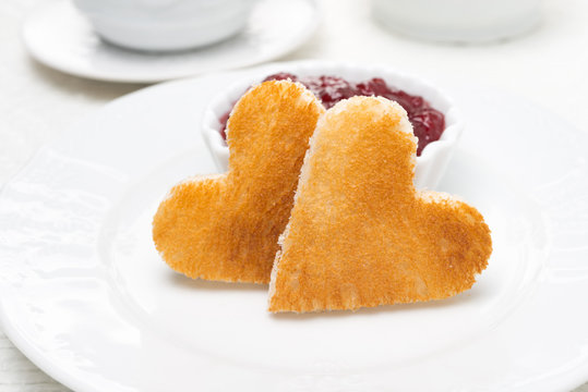 Two toast bread in the shape of hearts and berry jam