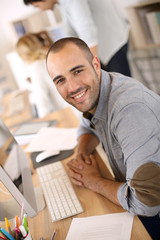 Cheerful guy sitting in front of desktop computer