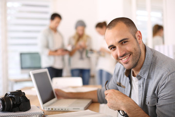 Obraz premium Cheerful reporter working in office on laptop