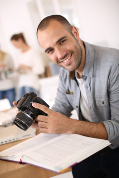 Cheerful reporter working in office on laptop