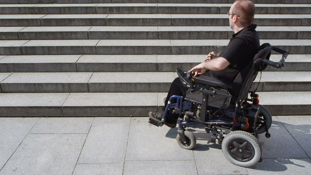 disabled person in an electric wheelchair approaches stairs high