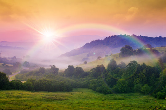 Fototapeta cold fog on hot sunrise in mountains. beautiful summer scenery with rainbow