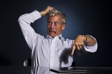 Upset frustrated senior man pointing at his tablet