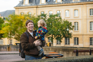 Adorable little son and father in autumn city.