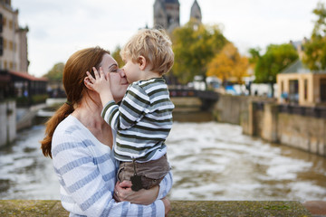 Fototapeta na wymiar Adorable little son and mother in autumn city.
