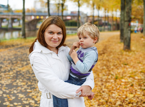 Adorable little son and mother in autumn city.