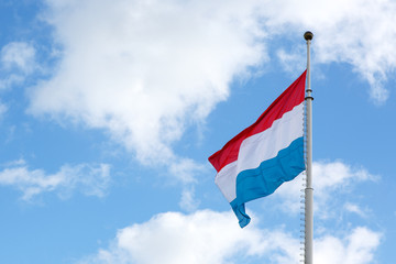 Luxembourg flag is waving in front of blue sky and puffy clouds