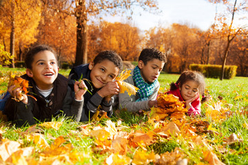 Group of kids lay in autumn leaves