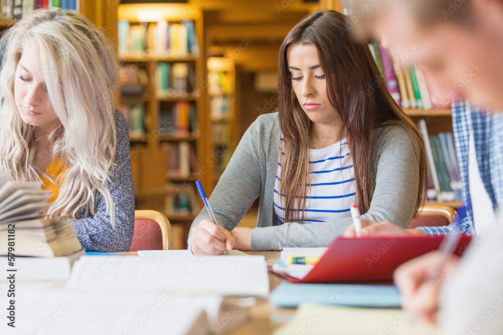 Poster students writing notes at library desk
