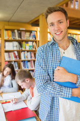 Male student with others in background at library