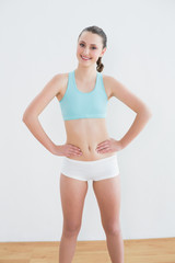 Fototapeta na wymiar Smiling toned woman standing in fitness studio