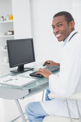 Fototapeta na wymiar Smiling male doctor using computer at medical office