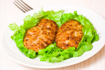 Burger with fresh green lettuce leaves on white dish