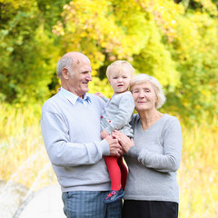 Happy grandparents with little baby granddaughter in the park
