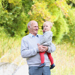 Happy grandfather with baby granddaughter in beautiful park