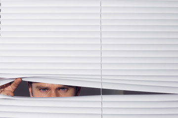 Businessman peeking through blinds