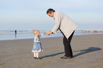 Happy father and daughter playing together on the beach