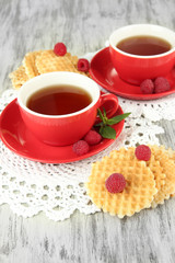 Cups of tea with cookies and raspberries on table close-up