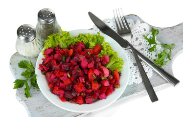 Beet salad on plate on napkin on wooden board isolated on white
